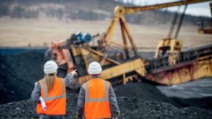 construction workers point at mining equipment in the near distance