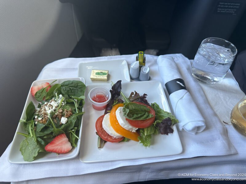 a plate of salad and a glass of water on a table