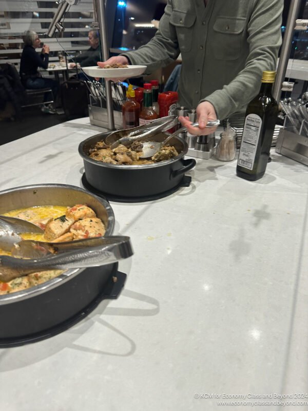 a man standing behind a counter with food in pots