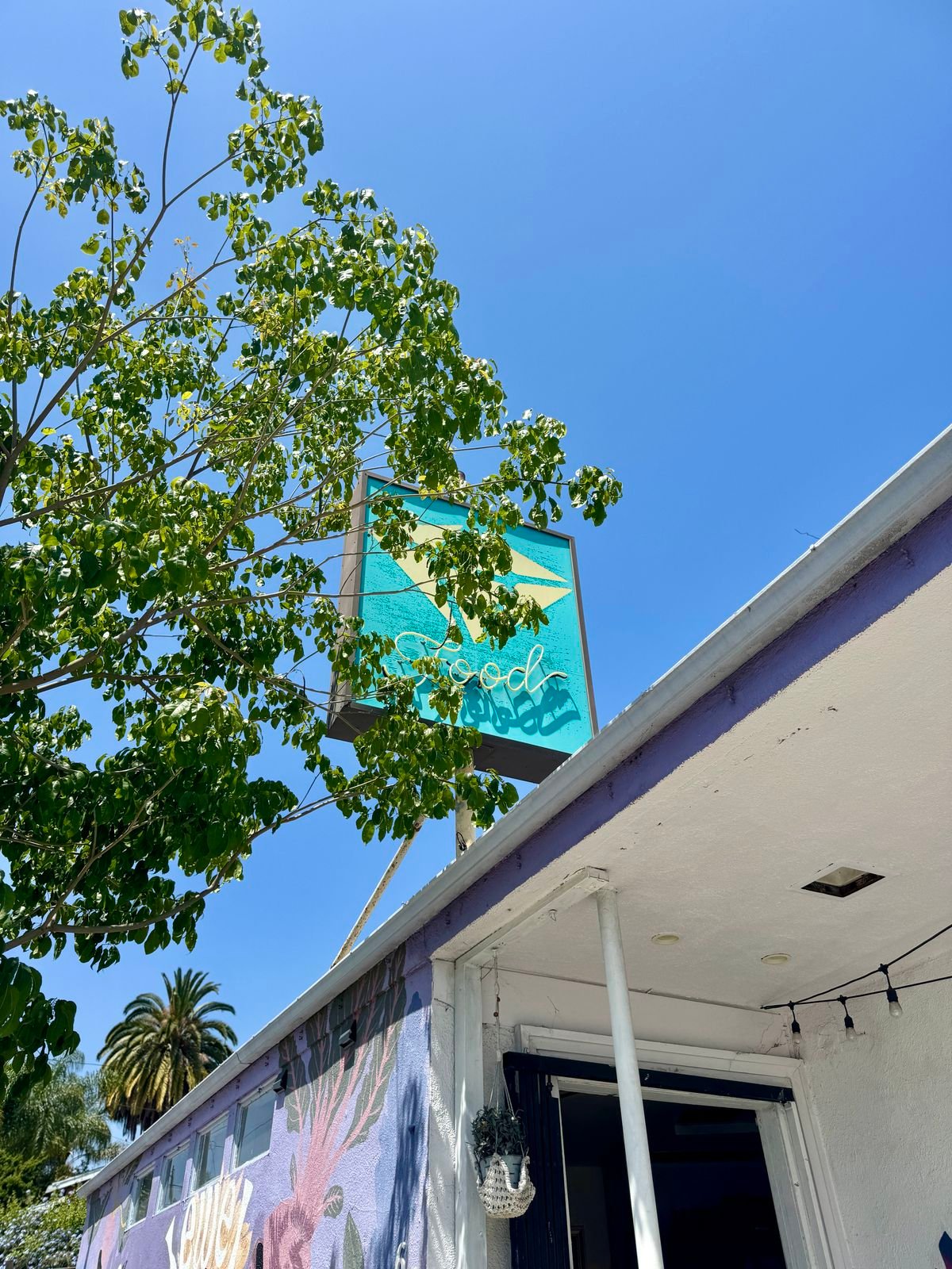 Turquoise Jewel sign above the restaurant covered partially by trees