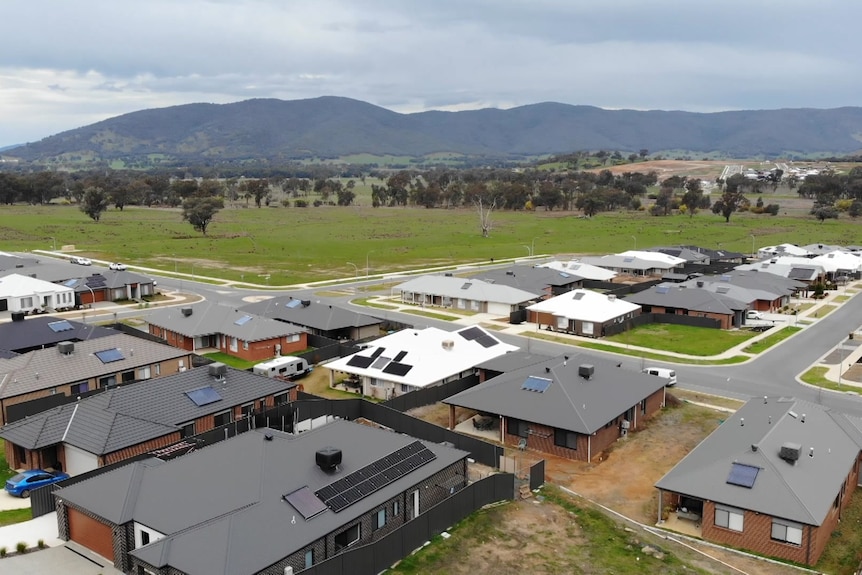 A drone shot of houses with a large paddock in the background 