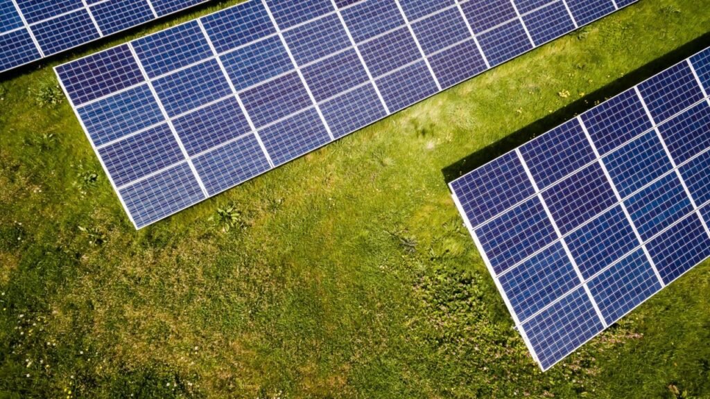 Solar panels from above on green grass, at a jaunty angle.